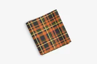A folded piece of black, orange, and green plaid fabric, possibly for PinkPantheress's custom ballet flats