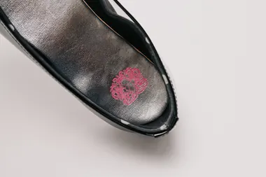 A close-up of PinkPantheress's custom unfinished ballet flats shows a pink embroidered skull logo on the silver insole